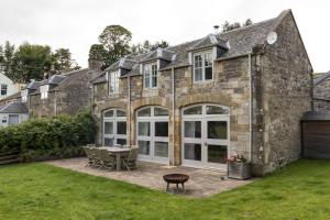 an external view of a stone house with a patio at The Coach House, Pentland Hills in Nine Mile Burn
