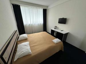 a hotel room with a bed and a television at Rustaveli Inn რუსთაველი ინნ in Rustavi