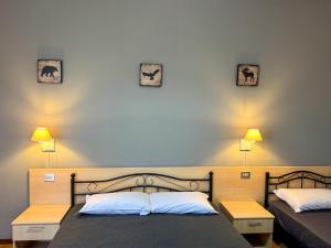 a bedroom with two beds and two lamps on the wall at Amica in Salsomaggiore Terme