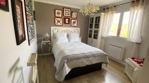 ein Schlafzimmer mit einem Bett mit weißen Laken und einem Kronleuchter in der Unterkunft Les Hortensias Du Monastère in Saint-Aubin-de-Médoc