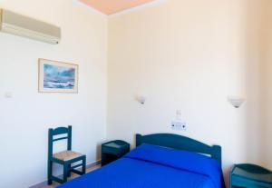 a bedroom with a blue bed and a chair at Panorama Hotel in Agia Marina Aegina