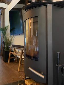 a stove in a living room with a table at Hunters Cabin - Rustic farm stay in Great Chart