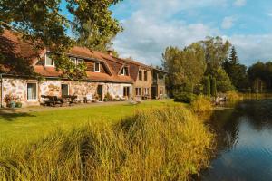 a stone house with a lake in front of it at Jeiskas dzirnavas in Launkalne