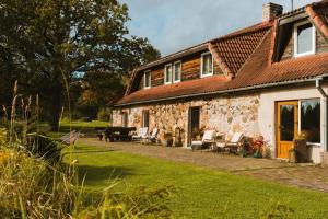 an old stone house with chairs and a patio at Jeiskas dzirnavas in Launkalne +71 photos