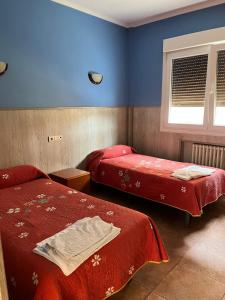 a bedroom with two beds and a window and blue walls at Pensión Agarimo in Trapagaran