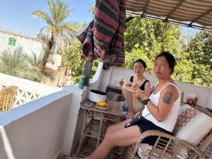 Una pareja de personas sentadas en un balcón comiendo comida. en Seko Kato Nile View Hostel, en Asuán