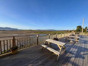 eine Reihe von Picknicktischen auf einer Terrasse in Strandnähe in der Unterkunft Harrapool Hideout Skye in Broadford