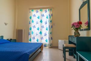 a bedroom with a bed and a dresser and a window at Panorama Hotel in Agia Marina Aegina