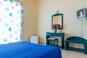 a bedroom with a blue bed and a table and a mirror at Panorama Hotel in Agia Marina Aegina