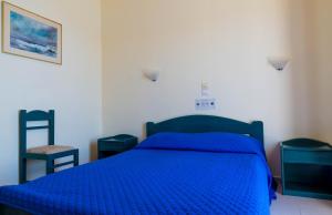 a bed with a blue comforter in a bedroom at Panorama Hotel in Agia Marina Aegina