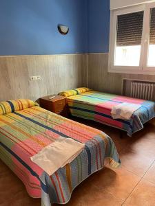 two beds in a room with blue walls at Pensión Agarimo in Trapagaran