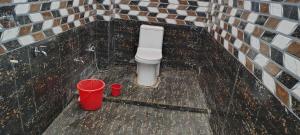 a bathroom with a toilet and two red buckets at Hotel O N P Grand and Resort in Manwān