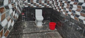a bathroom with a toilet and a red bucket at Hotel O N P Grand and Resort in Manwān