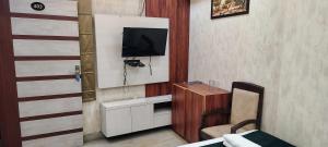 a room with a tv and a bed and a chair at Hotel O HOTE V-SQUARE in Bijnaur +18 photos