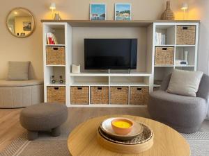Una sala de estar con un televisor y una mesa. en T2, 50 m beach, balcony with sea view, en La Teste-de-Buch