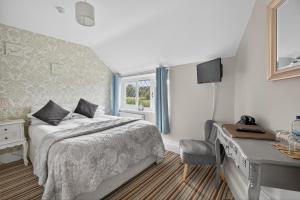a bedroom with a bed and a desk and a window at Greyhound Country Inn in Honiton