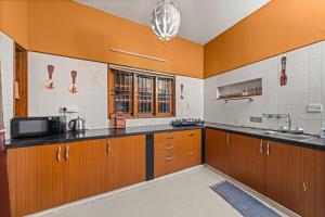 a large kitchen with wooden cabinets and a microwave at Bougain Blossom Spacez Luxury Villa with Terrace Garden in Bangalore