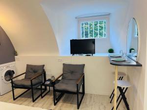 ein Zimmer mit zwei Stühlen, einem Tisch und einem Fernseher in der Unterkunft Studio Relaxe in Jougne