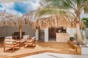 a patio with chairs and a table and a palm tree at NEW 6 Bed 6 Bath Pool - Bocobay Mangel Beach House in Savaneta