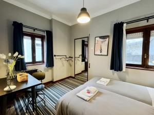 a room with two beds and a desk and windows at AC House in Porto