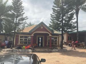 a small red house with people standing outside of it at Otam homes in Akure