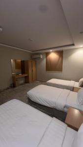 a hotel room with two beds and a desk at شقة بغرفتين نوم وصالة بدخول ذكي in Al Madinah