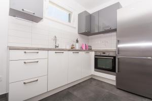 a kitchen with white cabinets and a stainless steel refrigerator at Villa Piramida in Trogir