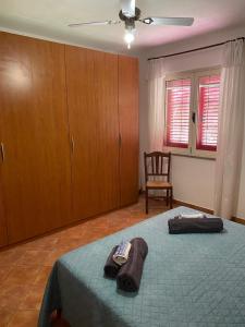 een slaapkamer met een bed, een stoel en ramen bij La Luna Sarda, Bosa in Bosa Marina