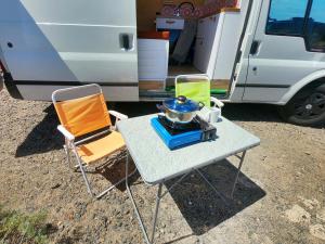 Una mesa con dos sillas y una olla encima al lado de una autocaravana. en Descubre Tenerife en furgoneta camper, en Los Abrigos