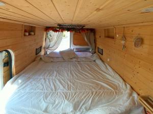 Una cama grande en una habitación pequeña en una cabaña de madera. en Descubre Tenerife en furgoneta camper, en Los Abrigos
