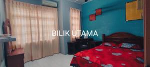 a bedroom with a red bed and a blue wall at NazAnie Homestay in Kota Tinggi