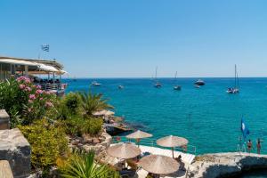 a beach with umbrellas and boats in the water at Panorama Hotel in Agia Marina Aegina