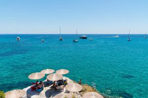 a group of people sitting on a beach with umbrellas at Panorama Hotel in Agia Marina Aegina
