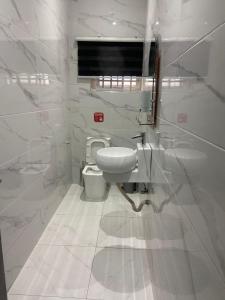 a white bathroom with a toilet and a window at Maxjen Executive Lodge in Amasaman +12 photos
