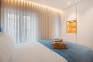a white bedroom with a bed with towels on it at Coastal Dreams - Casa Brisa in Nazaré