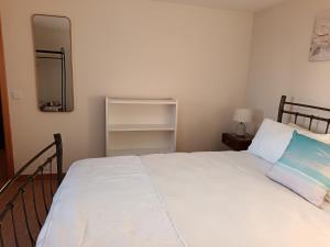 una camera da letto con un letto bianco e uno specchio di Adelaide's Cottage a Ponta do Pargo