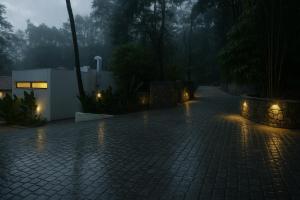马迪凯里Hillscape Resort的雨中湿漉漉的砖砌车道上，灯光闪烁