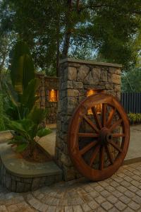 马迪凯里Hillscape Resort的院子里有一堵石墙，墙上挂着一个木制马车轮子