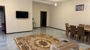 a living room with a table and a television on a wall at Moy goust house in Qusar