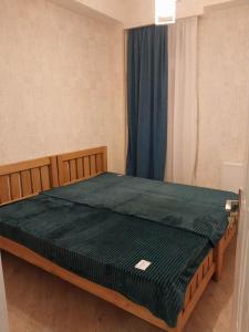 une chambre avec un grand lit avec une couette verte dans l'établissement Apart Fenix, à Stantsiya Mukhiani