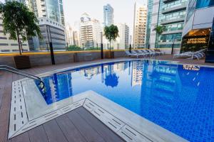 a swimming pool in a city with tall buildings at Golden Tulip Media Hotel in Dubai