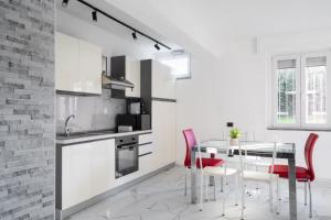 uma cozinha com uma mesa de jantar e cadeiras vermelhas em Rifugio Elegante a due passi dal Lago - Free Wifi Giardino e AC em Sarnico