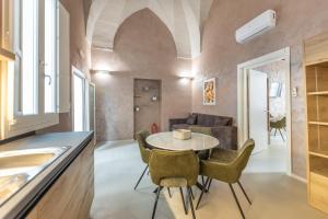 Dimora Suite Oro في غالّيبولي: مطبخ وغرفة معيشة مع طاولة وكراسي