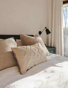 uma cama branca com almofadas e um candeeiro em Casa Tirthan Valley em Bashist