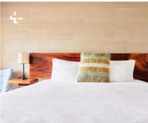 um quarto com uma cama branca com cabeceira de madeira em Casa Tirthan Valley em Bashist