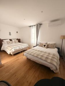 two beds in a room with wooden floors at Mas de la Huppe - Franquevaux en Petite Camargue in Beauvoisin