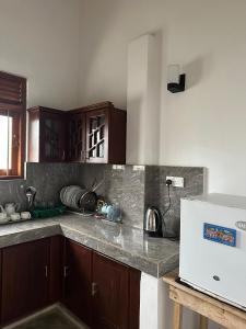 a kitchen with wooden cabinets and a white refrigerator at Royal Resort in Weligama