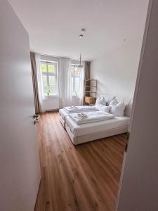 ein weißes Schlafzimmer mit einem Bett und Holzboden in der Unterkunft Celle Appartement - 2 Schlafzimmer, Designermöbel und Frühstück in Celle