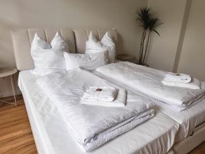 ein Bett mit weißen Laken und Handtüchern darauf in der Unterkunft Celle Appartement - 2 Schlafzimmer, Designermöbel und Frühstück in Celle