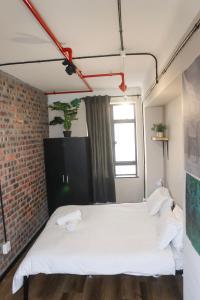 a bedroom with a white bed and a brick wall at Chill Flamingo in Cape Town